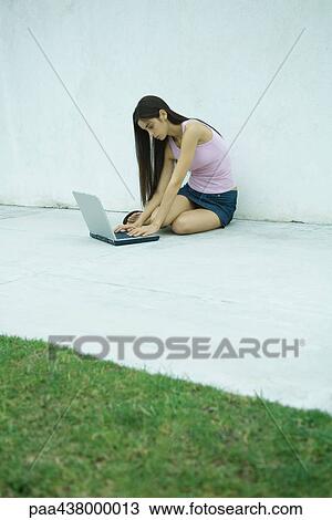 Woman sitting on ground using laptop, full length View Large Photo Image Stock Image - Woman sitting on ground using laptop, full length. Fotosearch