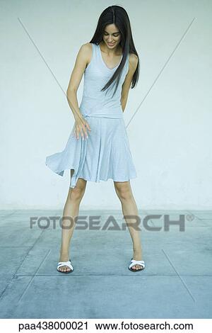Woman standing while dress swings, looking down, full length View Large Photo Image Stock Image - Woman standing while dress swings, looking down, full length. Fotosearch