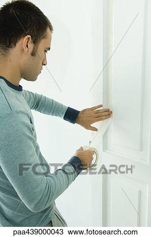 Man applying masking tape to door View Large Photo Image Stock Image - Man applying masking tape to door. Fotosearch