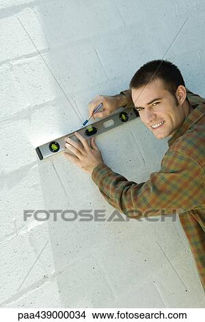 Man drawing line on wall with level View Large Photo Image Picture - Man drawing line on wall with level. Fotosearch