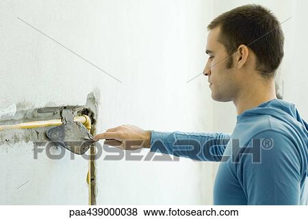 Man filling in hole around plumbing in wall with grout View Large Photo Image Stock Photo - Man filling in hole around plumbing in wall with grout. Fotosearch