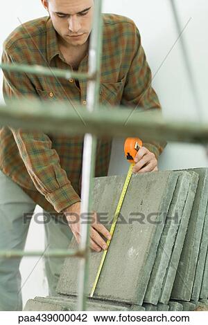 Stock Image - Man measuring tiles. Fotosearch
