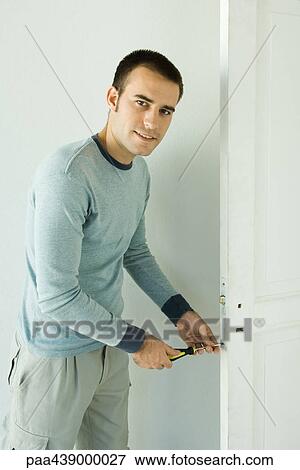 Man unscrewing lock on door View Large Photo Image Stock Photo - Man unscrewing lock on door. Fotosearch