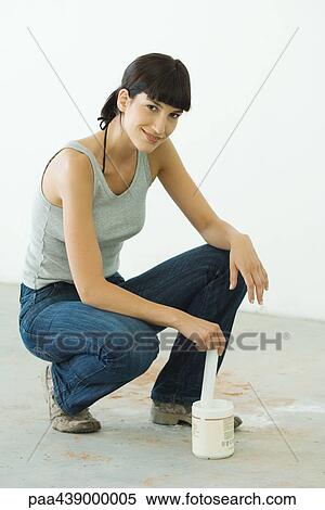 Woman crouching next to paint can, smiling at camera View Large Photo Image Stock Photography - Woman crouching next to paint can, smiling at camera. Fotosearch