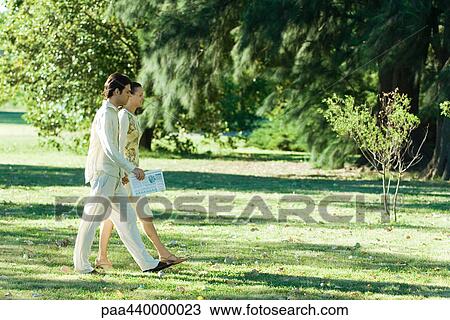 Couple walking across grass together View Large Photo Image Stock Image - Couple walking across grass together. Fotosearch