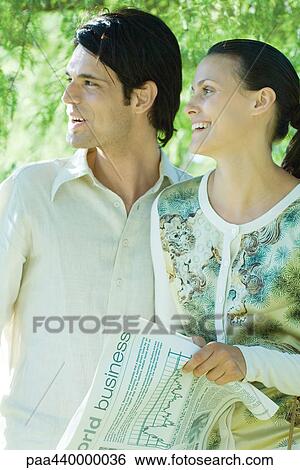 Couple, woman holding newspaper, both looking out of frame View Large Photo Image Stock Photograph - Couple, woman holding newspaper, both looking out of frame. Fotosearch