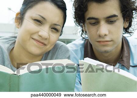 Young adult couple reading outdoors, close-up View Large Photo Image Stock Photo - Young adult couple reading outdoors, close-up. Fotosearch