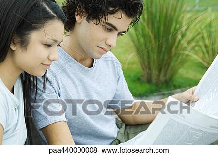 Stock Photo - Young couple reading newspaper outdoors together. Fotosearch