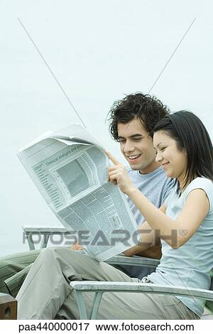 Young couple reading newspaper View Large Photo Image Stock Photo - Young couple reading newspaper. Fotosearch