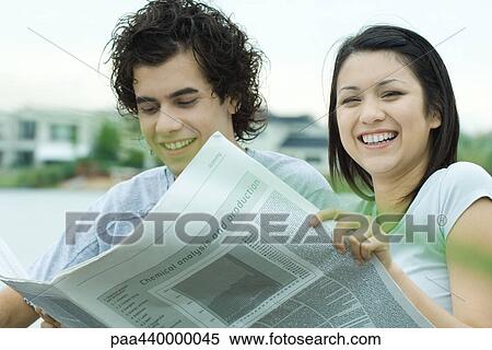 Young couple reading newspaper together outdoors View Large Photo Image Stock Photography - Young couple reading newspaper together outdoors. Fotosearch
