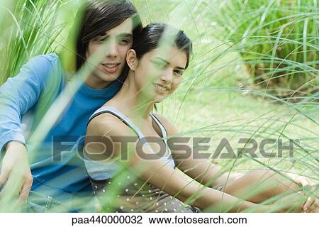 Young couple sitting on grass together View Large Photo Image Stock Image - Young couple sitting on grass together. Fotosearch