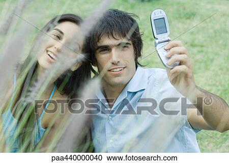 Young couple taking photos of selves with cell phone View Large Photo Image Stock Image - Young couple taking photos of selves with cell phone. Fotosearch