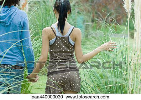 Young couple walking in grass View Large Photo Image Stock Image - Young couple walking in grass. Fotosearch