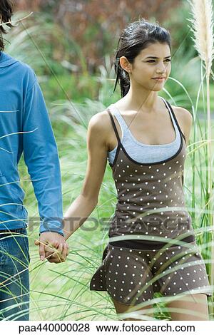 Young couple walking through grass, holding hands View Large Photo Image Stock Photo - Young couple walking through grass, holding hands. Fotosearch