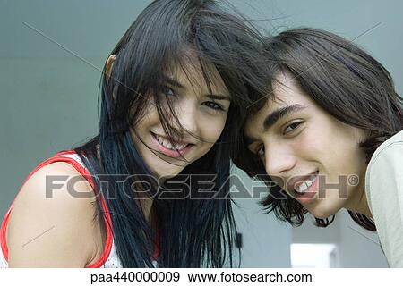 Young couple with heads together, smiling at camera View Large Photo Image Stock Photo - Young couple with heads together, smiling at camera. Fotosearch