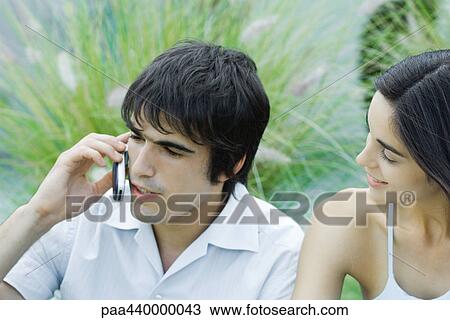 Young man using cell phone while girlfriend waits View Large Photo Image Stock Image - Young man using cell phone while girlfriend waits. Fotosearch