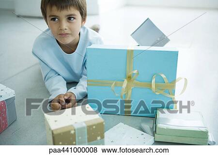 Boy lying on floor next to Christmas presents View Large Photo Image Stock Photo - Boy lying on floor next to Christmas presents. Fotosearch