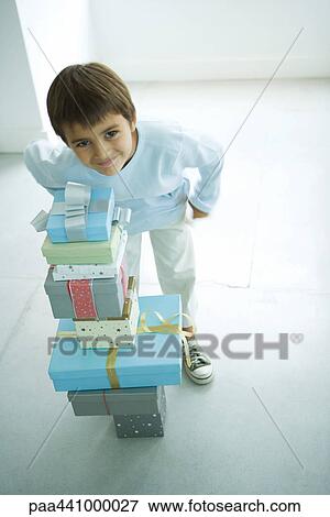 Boy standing next to stack of Christmas presents View Large Photo Image Stock Photo - Boy standing next to stack of Christmas presents. Fotosearch