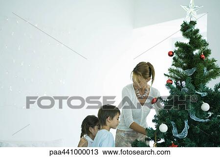 Stock Image - Family decorating Christmas tree. Fotosearch
