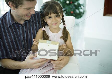 Stock Photo - Man holding daughter Christmas present. Fotosearch