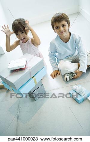 Two children sitting on floor with stack of presents View Large Photo Image Stock Photo - Two children sitting on floor with stack of presents. Fotosearch