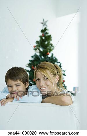 Woman and son sitting on couch in front of Christmas tree View Large Photo Image Stock Image - Woman and son sitting on couch in front of Christmas tree. Fotosearch