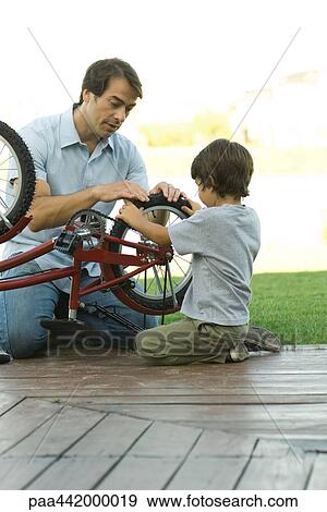 Father and son fixing bike together View Large Photo Image Stock Photo - Father and son fixing bike together. Fotosearch