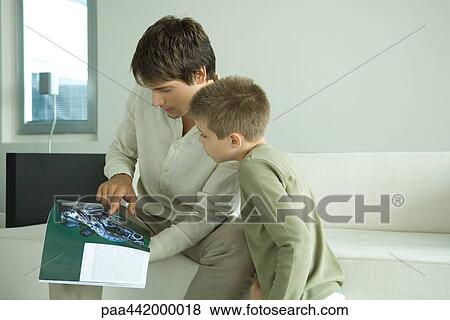 Stock Photo - Father and son looking at magazine together. Fotosearch
