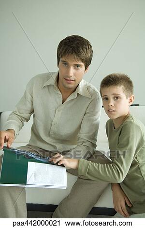 Father and son looking up from magazine View Large Photo Image Stock Image - Father and son looking up from magazine. Fotosearch