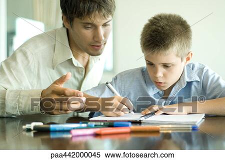 Father and son, man looking over boy's shoulder as he does homework View Large Photo Image Stock Photography - Father and son, man looking over boy's shoulder as he does homework. Fotosearch