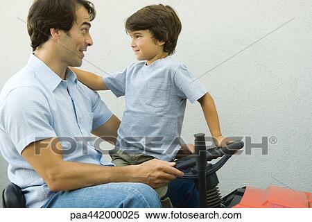 Stock Photography - Father and son on riding lawnmower together. Fotosearch