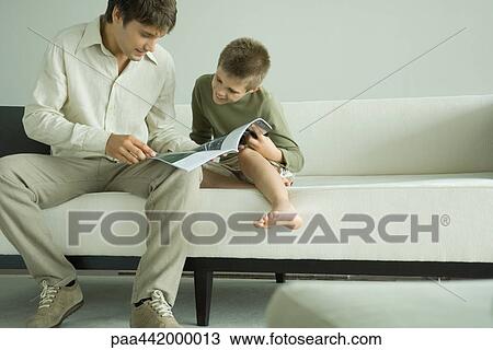 Father and son reading magazine together View Large Photo Image Stock Image - Father and son reading magazine together. Fotosearch