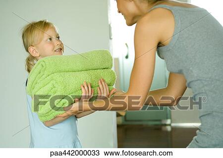 Girl handing mother stack of folded towels View Large Photo Image Stock Image - Girl handing mother stack of folded towels. Fotosearch