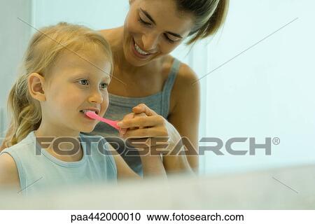 Mother and daughter brushing girl's teeth together View Large Photo Image Stock Image - Mother and daughter brushing girl's teeth together. Fotosearch