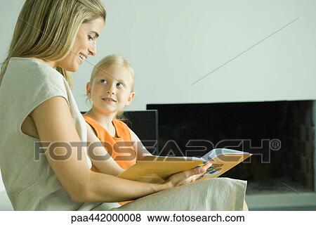 Stock Photo - Mother and daughter reading book together. Fotosearch
