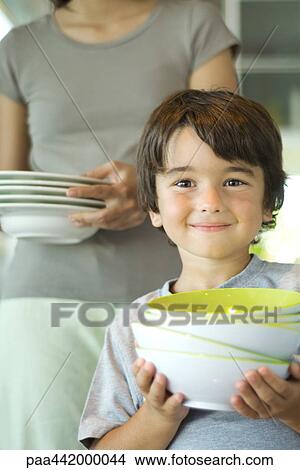 Mother and son carrying dishes together View Large Photo Image Picture - Mother and son carrying dishes together. Fotosearch