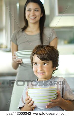 Mother and son carrying stacks of dishes View Large Photo Image Stock Image - Mother and son carrying stacks of dishes. Fotosearch