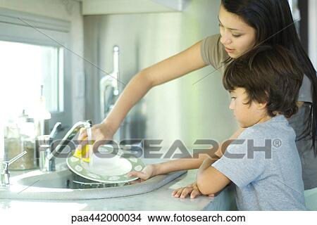 Mother and son washing dishes View Large Photo Image Picture - Mother and son washing dishes. Fotosearch