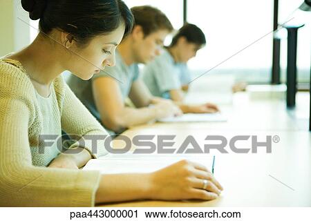 Stock Image - College students sitting at table, studying. Fotosearch
