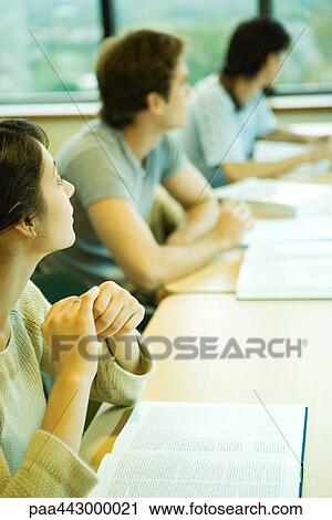 Stock Image - College students sitting at table, looking out window. Fotosearch