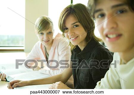 Stock Photo - College students sitting at table, smiling at camera. Fotosearch