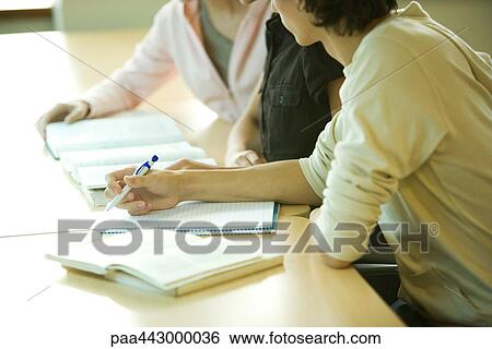 Stock Photograph - College students sitting at table studying, partial view. Fotosearch