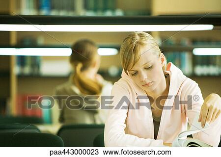 Female college student sitting at table in library, studying View Large Photo Image Stock Image - Female college student sitting at table in library, studying. Fotosearch