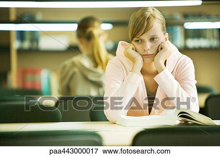 Female college student sitting at table in library, leaning on elbows View Large Photo Image Stock Photo - Female college student sitting at table in library, leaning on elbows. Fotosearch