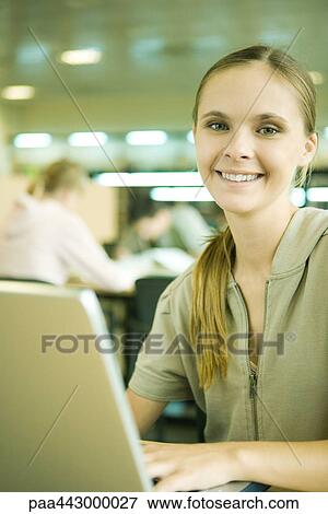 Female college student sitting at table in library, using laptop View Large Photo Image Stock Photo - Female college student sitting at table in library, using laptop. Fotosearch