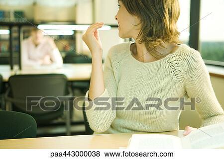 Female college student sitting at table in library, looking over shoulder View Large Photo Image Stock Photo - Female college student sitting at table in library, looking over shoulder. Fotosearch