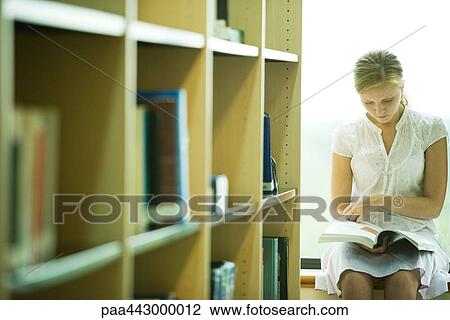 Female college student sitting in library, reading book View Large Photo Image Stock Image - Female college student sitting in library, reading book . Fotosearch