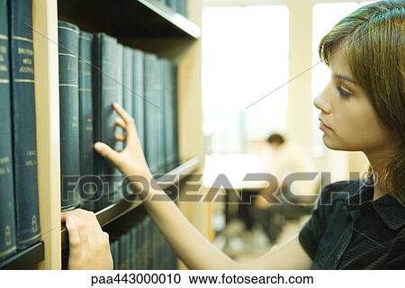 Female college student taking book from shelf in library View Large Photo Image Stock Image - Female college student taking book from shelf in library. Fotosearch