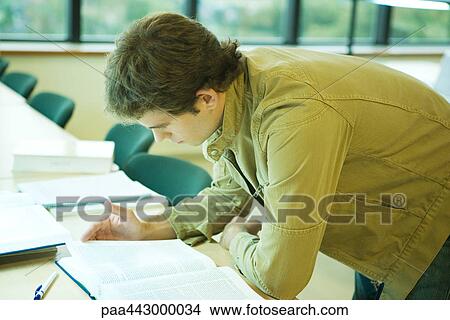 Male college student leaning forward on table, studying View Large Photo Image Picture - Male college student leaning forward on table, studying. Fotosearch