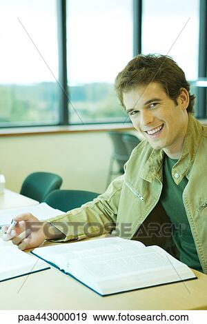 Male college student sitting in library, smiling at camera View Large Photo Image Stock Photo - Male college student sitting in library, smiling at camera. Fotosearch
